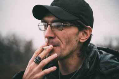 Bir adam sigara içiyor. Gözlüklü adam sigara içiyor. Tütün duman