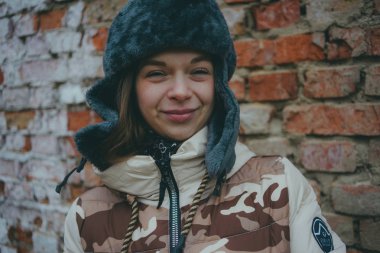 Yetişkin kız sokak giysileri üzerinde kırmızı tuğla duvar arka plan kopya alanı ile ayakta. Bir tuğla duvar arka planda kadın.