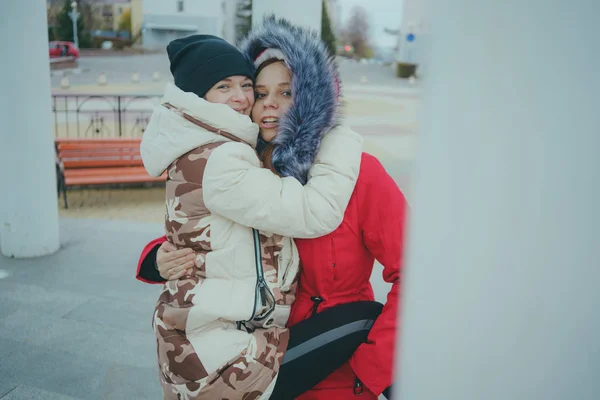 Two girls on a walk, meeting friends in cold weather, women warmed up in warm jackets, the concept of female friendship.