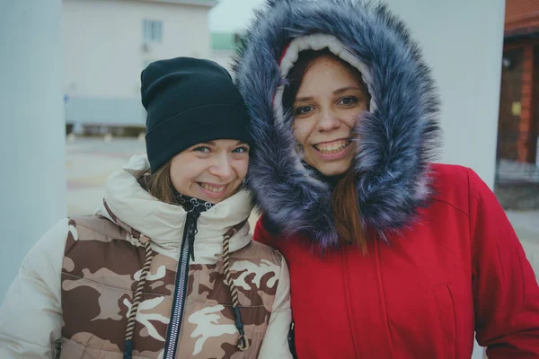 Two girls on a walk, meeting friends in cold weather, women warmed up in warm jackets, the concept of female friendship.