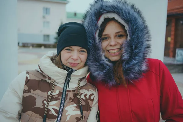 Two girls on a walk, meeting friends in cold weather, women warmed up in warm jackets, the concept of female friendship.