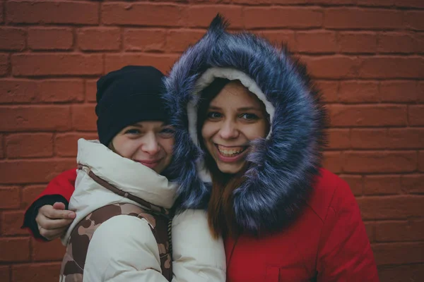 Two girls on a walk, meeting friends in cold weather, women warmed up in warm jackets, the concept of female friendship.