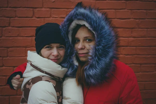 Two girls on a walk, meeting friends in cold weather, women warmed up in warm jackets, the concept of female friendship.