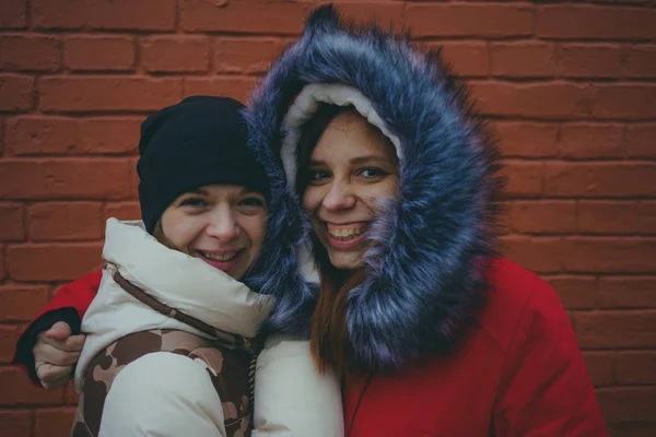 Two girls on a walk, meeting friends in cold weather, women warmed up in warm jackets, the concept of female friendship.