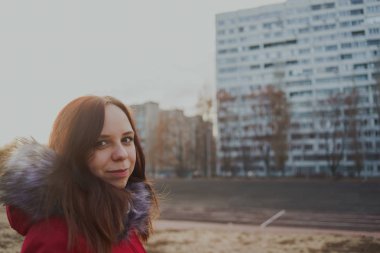 Bulutlu bir günde dışında poz bir kırmızı ceketli mutlu güzel genç kız. duygusal bir öğrenci portresi. sokak stili