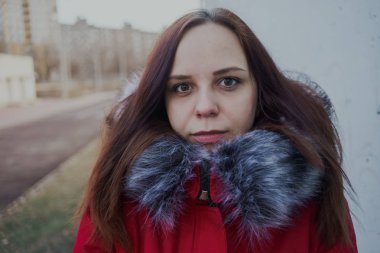 Bulutlu bir günde dışında poz bir kırmızı ceketli mutlu güzel genç kız. duygusal bir öğrenci portresi. sokak stili