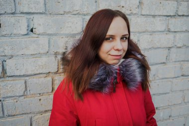 Bulutlu bir günde dışında poz bir kırmızı ceketli mutlu güzel genç kız. duygusal bir öğrenci portresi. sokak stili