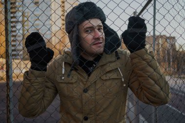 Cap güzelliğini ile mutlu yakışıklı genç adam. Kürk şapka genç adam. bulutlu bir günde sokakta duran genç bir adam. duygusal bir öğrenci portresi. sokak stili