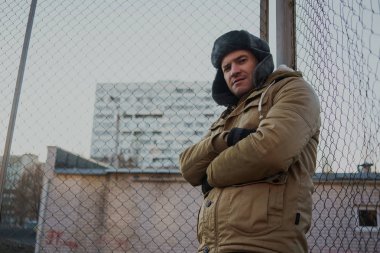 Cap güzelliğini ile mutlu yakışıklı genç adam. Kürk şapka genç adam. bulutlu bir günde sokakta duran genç bir adam. duygusal bir öğrenci portresi. sokak stili