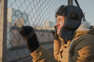 Cap güzelliğini ile mutlu yakışıklı genç adam. Kürk şapka genç adam. bulutlu bir günde sokakta duran genç bir adam. duygusal bir öğrenci portresi. sokak stili