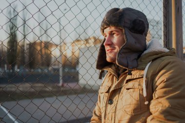 Cap güzelliğini ile mutlu yakışıklı genç adam. Kürk şapka genç adam. bulutlu bir günde sokakta duran genç bir adam. duygusal bir öğrenci portresi. sokak stili