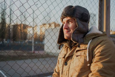 Cap güzelliğini ile mutlu yakışıklı genç adam. Kürk şapka genç adam. bulutlu bir günde sokakta duran genç bir adam. duygusal bir öğrenci portresi. sokak stili