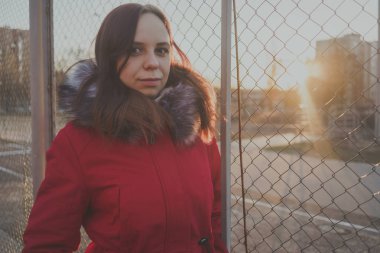 Bulutlu bir günde dışında poz bir kırmızı ceketli mutlu güzel genç kız. duygusal bir öğrenci portresi. sokak stili