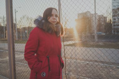 Bulutlu bir günde dışında poz bir kırmızı ceketli mutlu güzel genç kız. duygusal bir öğrenci portresi. sokak stili