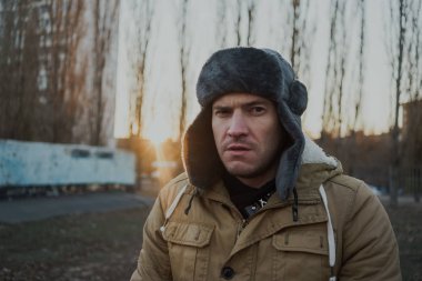 Cap güzelliğini ile mutlu yakışıklı genç adam. Kürk şapka genç adam. bulutlu bir günde sokakta duran genç bir adam. duygusal bir öğrenci portresi. sokak stili