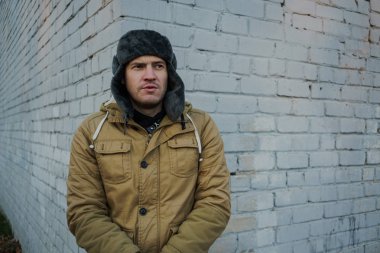 Cap güzelliğini ile mutlu yakışıklı genç adam. Kürk şapka genç adam. bulutlu bir günde sokakta duran genç bir adam. duygusal bir öğrenci portresi. sokak stili