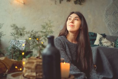 Kız sersem kanepe, rahat bir oda arka planı yakın katta oturuyor. Konsept: romantizm ve rüyalar