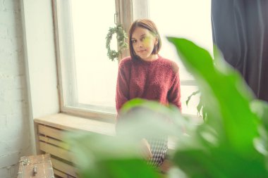 Pencerenin kız oturur, öğrenci düşünceli görünüyor. Model pencerenin önünde poz. Konsept: romantizm ve özlem