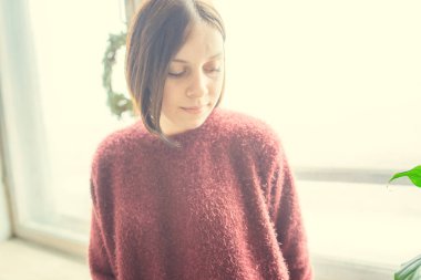 Pencerenin kız oturur, öğrenci düşünceli görünüyor. Model pencerenin önünde poz. Konsept: romantizm ve özlem