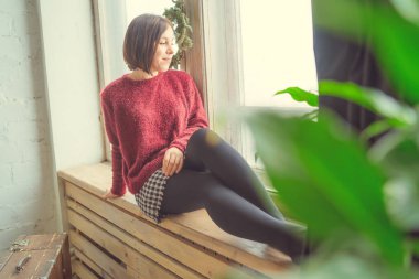 Pencerenin kız oturur, öğrenci düşünceli görünüyor. Model pencerenin önünde poz. Konsept: romantizm ve özlem