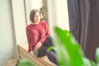 Pencerenin kız oturur, öğrenci düşünceli görünüyor. Model pencerenin önünde poz. Konsept: romantizm ve özlem