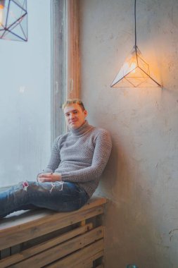 Yakışıklı olan büyük bir pencere arka pencere kenarında oturan. Adam hayal bir şey yönünde görünüyor.