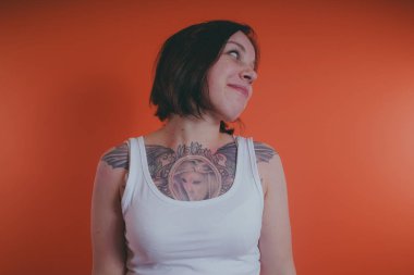 Göğsüne, dövmeli kız turuncu bir arka plan üzerinde poz