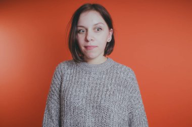 Genç kız sıcak gri süveterli kadın örme kazaklı kısa saç kesimi, metin için yer ile turuncu arka plan üzerinde poz