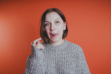 Genç kız sıcak gri süveterli kadın örme kazaklı kısa saç kesimi, metin için yer ile turuncu arka plan üzerinde poz