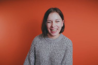 Genç kız sıcak gri süveterli kadın örme kazaklı kısa saç kesimi, metin için yer ile turuncu arka plan üzerinde poz