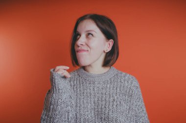 Genç kız sıcak gri süveterli kadın örme kazaklı kısa saç kesimi, metin için yer ile turuncu arka plan üzerinde poz