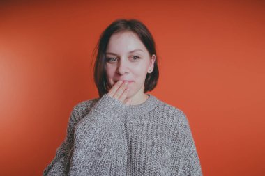 Genç kız sıcak gri süveterli kadın örme kazaklı kısa saç kesimi, metin için yer ile turuncu arka plan üzerinde poz