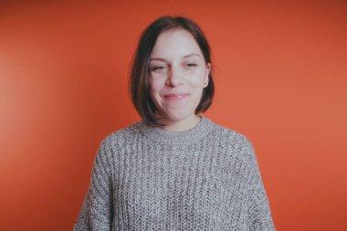 Genç kız sıcak gri süveterli kadın örme kazaklı kısa saç kesimi, metin için yer ile turuncu arka plan üzerinde poz