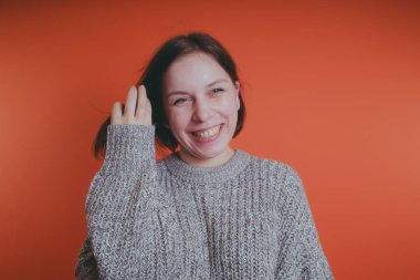 Genç kız sıcak gri süveterli kadın örme kazaklı kısa saç kesimi, metin için yer ile turuncu arka plan üzerinde poz