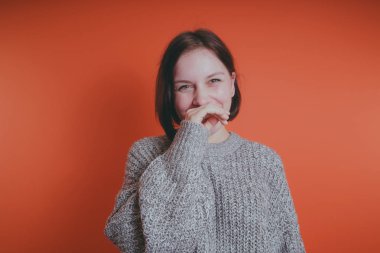 Genç kız sıcak gri süveterli kadın örme kazaklı kısa saç kesimi, metin için yer ile turuncu arka plan üzerinde poz