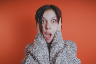 Genç kız sıcak gri süveterli kadın örme kazaklı kısa saç kesimi, metin için yer ile turuncu arka plan üzerinde poz