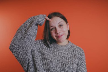 Genç kız sıcak gri süveterli kadın örme kazaklı kısa saç kesimi, metin için yer ile turuncu arka plan üzerinde poz