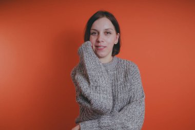 Genç kız sıcak gri süveterli kadın örme kazaklı kısa saç kesimi, metin için yer ile turuncu arka plan üzerinde poz