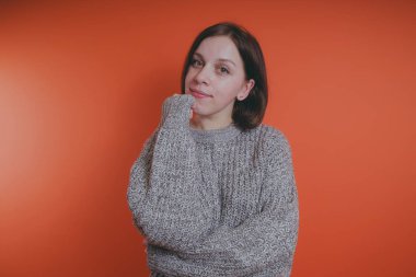 Genç kız sıcak gri süveterli kadın örme kazaklı kısa saç kesimi, metin için yer ile turuncu arka plan üzerinde poz