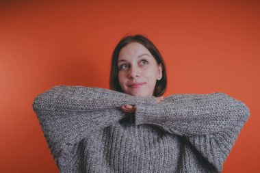 Genç kız sıcak gri süveterli kadın örme kazaklı kısa saç kesimi, metin için yer ile turuncu arka plan üzerinde poz