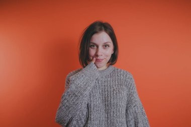 Genç kız sıcak gri süveterli kadın örme kazaklı kısa saç kesimi, metin için yer ile turuncu arka plan üzerinde poz