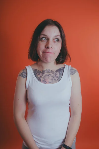 Κορίτσι Ένα Τατουάζ Στο Στήθος Της Θέτοντας Πορτοκαλί Φόντο — Φωτογραφία Αρχείου
