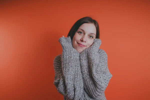 Young girl in warm grey sweater posing on orange background, woman with short haircut in knitted sweater, space for text