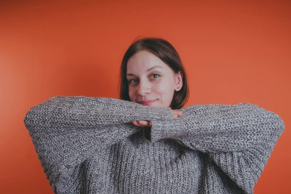 Genç kız sıcak gri süveterli kadın örme kazaklı kısa saç kesimi, metin için yer ile turuncu arka plan üzerinde poz