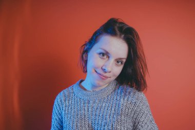 Genç kız sıcak gri süveterli kadın örme kazaklı kısa saç kesimi, metin için yer ile turuncu arka plan üzerinde poz