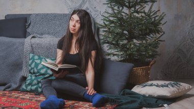 Kız sersem kanepe, rahat bir oda arka planı yakın katta oturuyor. Konsept: romantizm ve rüyalar