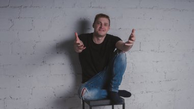 Siyah bir tişört, bir gri tuğla duvara yakışıklı bir adam. Acımasız adam dövme olan