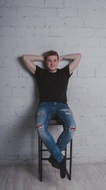 Siyah bir tişört, bir gri tuğla duvara yakışıklı bir adam. Acımasız adam dövme olan