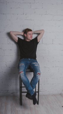 Siyah bir tişört, bir gri tuğla duvara yakışıklı bir adam. Acımasız adam dövme olan