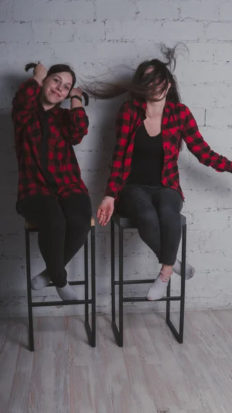 Duas Meninas Camisas Xadrez Vermelho Preto Sentado Cadeiras Fundo Parede — Fotografia de Stock